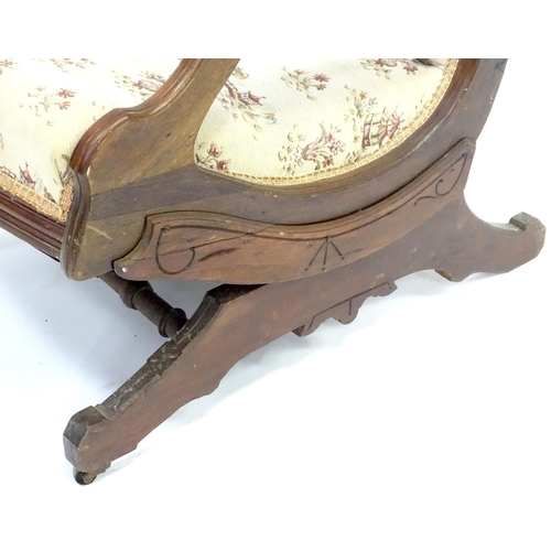 643 - An early 20thC rocking chair with carved cresting rail above a chamfered frame, with upholstered bac... 