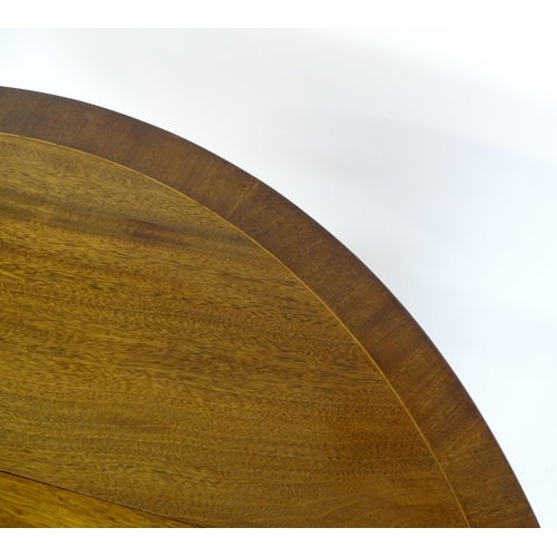 655 - A mid / late 20thC mahogany drop flap dining table, having a crossbanded and reeded rotating top rai... 