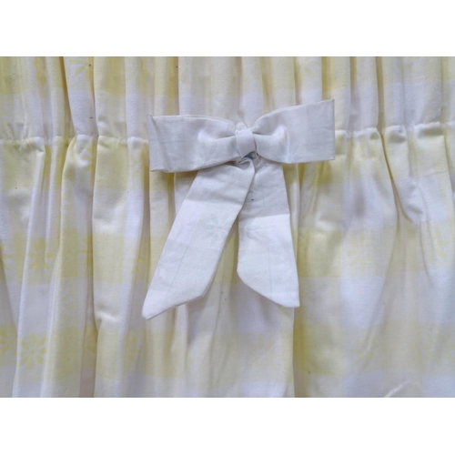 657 - A pair of curtains decorated in a yellow and white check pattern with bow detail. Together with a ma... 