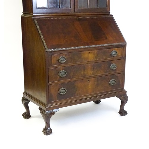 664 - An early 20thC mahogany bureau bookcase with a carved cornice above two astragal glazed doors and a ... 