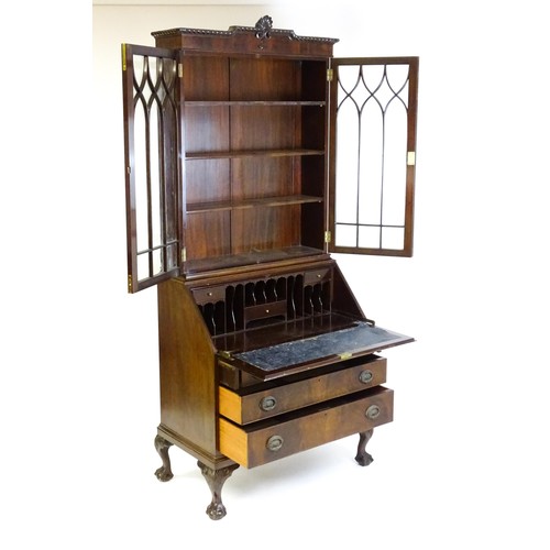 664 - An early 20thC mahogany bureau bookcase with a carved cornice above two astragal glazed doors and a ... 