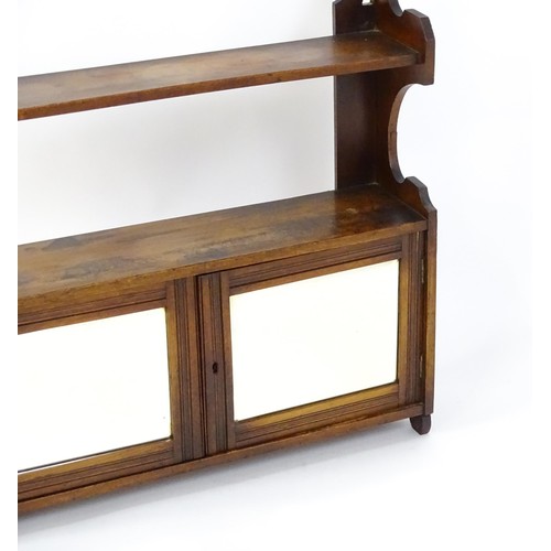 668 - An early 20thC wall hanging mahogany cabinet with two mirrored doors. 23 1/2