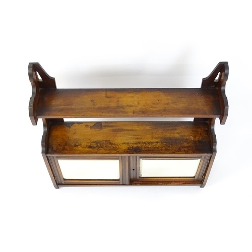 668 - An early 20thC wall hanging mahogany cabinet with two mirrored doors. 23 1/2