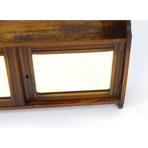 668 - An early 20thC wall hanging mahogany cabinet with two mirrored doors. 23 1/2