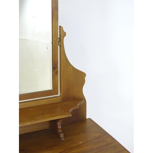 740 - An early 20thC mahogany dressing table with a shaped upstand, shelf and arched mirror. The top havin... 