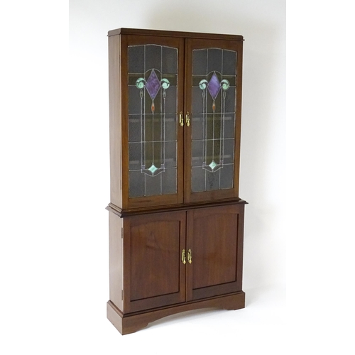 763 - An early / mid 20thC mahogany bookcase with stained and leaded glass panels above two panelled cupbo... 