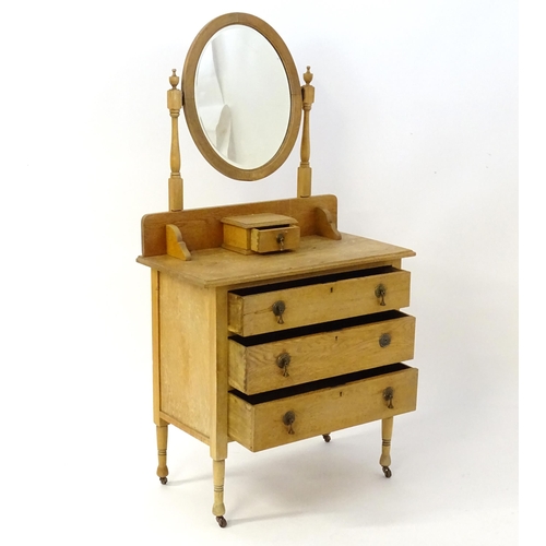 41 - An early 20thC oak dressing table with an oval mirror above three long drawers. 33