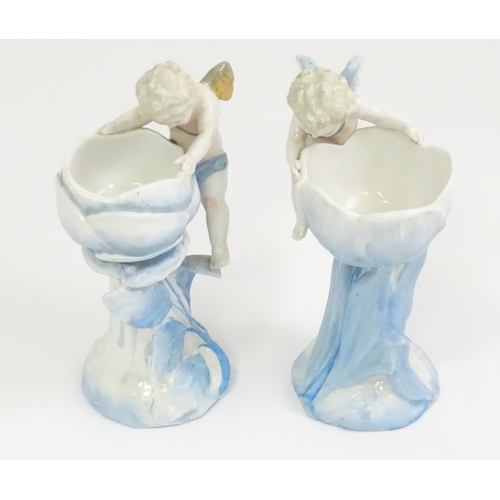 410 - A pair of German posy holders / bud vases of flower form with cherub detail. Impressed mark under SP... 