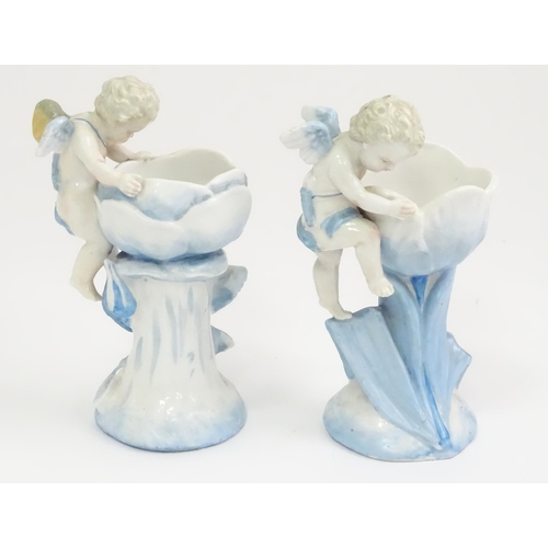 410 - A pair of German posy holders / bud vases of flower form with cherub detail. Impressed mark under SP... 