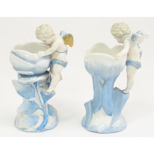 410 - A pair of German posy holders / bud vases of flower form with cherub detail. Impressed mark under SP... 