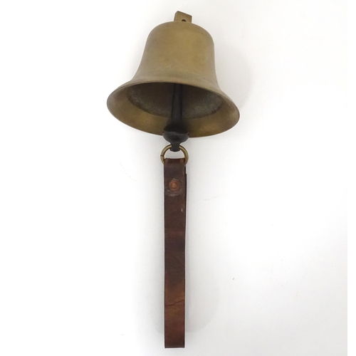 49 - A late 19thC brass hanging bell with leather strap, approx 5 1/2