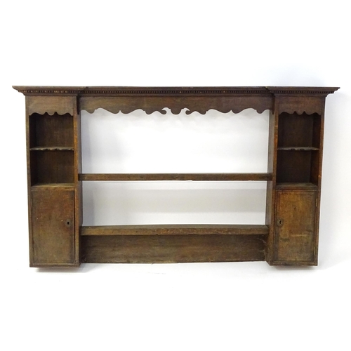 683 - An 18thC oak plate rack with a moulded cornice above a shaped frieze and two cupboards. 74