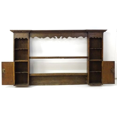 683 - An 18thC oak plate rack with a moulded cornice above a shaped frieze and two cupboards. 74