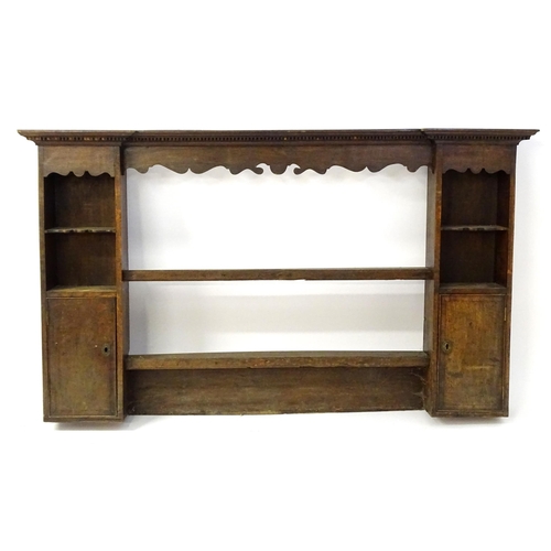 683 - An 18thC oak plate rack with a moulded cornice above a shaped frieze and two cupboards. 74