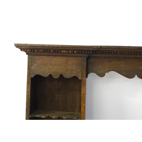 683 - An 18thC oak plate rack with a moulded cornice above a shaped frieze and two cupboards. 74