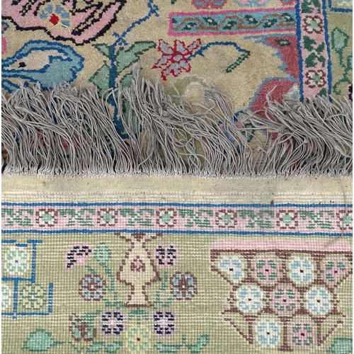 701 - Carpet / Rug : A cream and green ground rug profusely decorated with floral detail with vases, trees... 