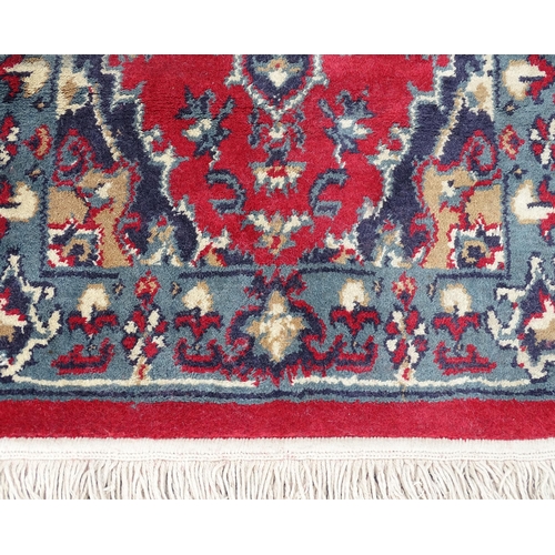 702 - Carpet / Rug : A pair of red and blue ground rugs with floral and folate detail.  Each approx 53