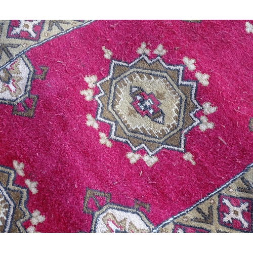 704 - Carpets/ Rugs :  Three red ground rugs with repeating geometric motifs.  Approx 37