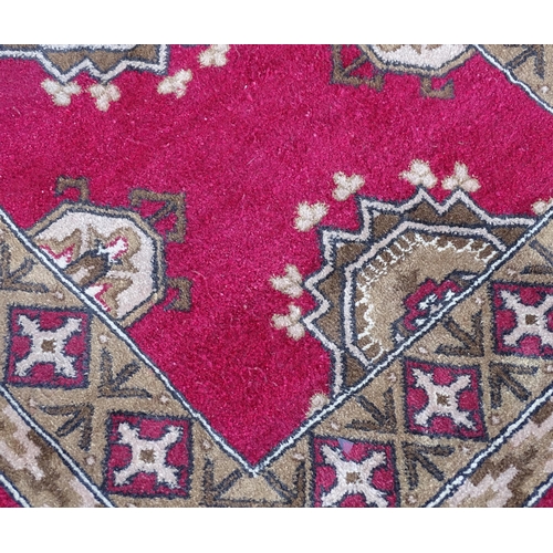 704 - Carpets/ Rugs :  Three red ground rugs with repeating geometric motifs.  Approx 37