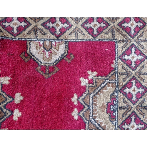 704 - Carpets/ Rugs :  Three red ground rugs with repeating geometric motifs.  Approx 37