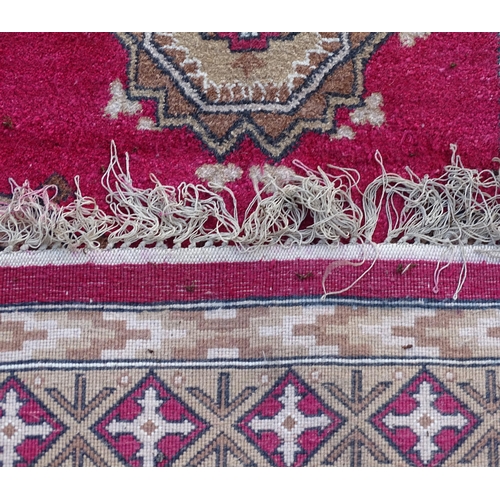 704 - Carpets/ Rugs :  Three red ground rugs with repeating geometric motifs.  Approx 37