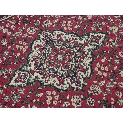705 - Carpet / Rug : A red ground rug with floral and foliate detail. Approx 66