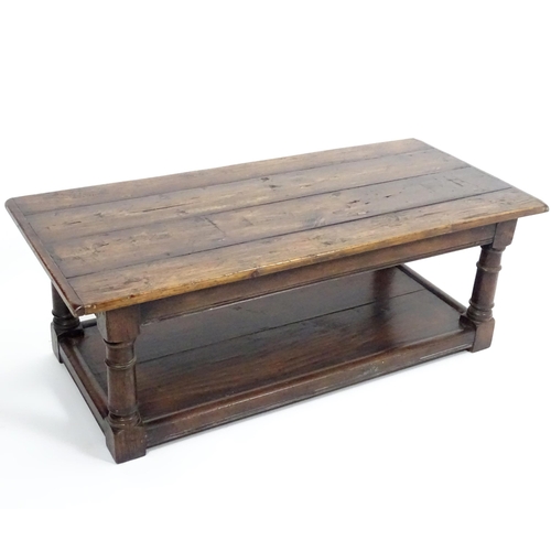 887 - An early 20thC oak coffee table with a planked rectangular top raised on four turned legs united by ... 