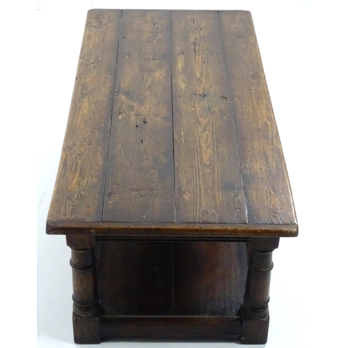 887 - An early 20thC oak coffee table with a planked rectangular top raised on four turned legs united by ... 