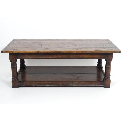 887 - An early 20thC oak coffee table with a planked rectangular top raised on four turned legs united by ... 