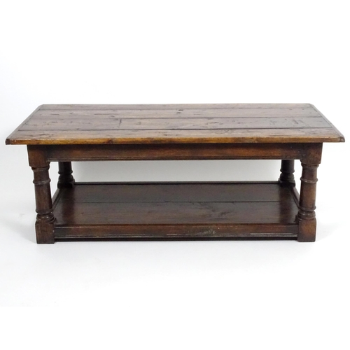 887 - An early 20thC oak coffee table with a planked rectangular top raised on four turned legs united by ... 