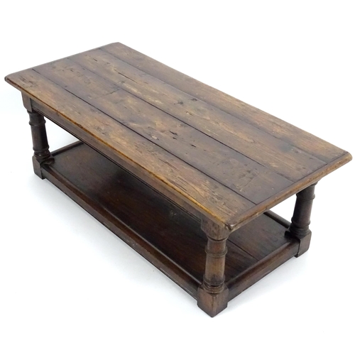 887 - An early 20thC oak coffee table with a planked rectangular top raised on four turned legs united by ... 