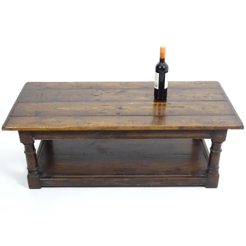 887 - An early 20thC oak coffee table with a planked rectangular top raised on four turned legs united by ... 