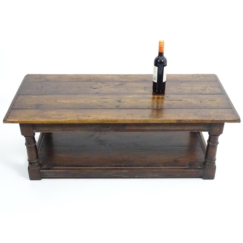 887 - An early 20thC oak coffee table with a planked rectangular top raised on four turned legs united by ... 