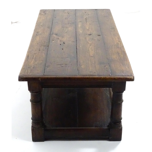 887 - An early 20thC oak coffee table with a planked rectangular top raised on four turned legs united by ... 