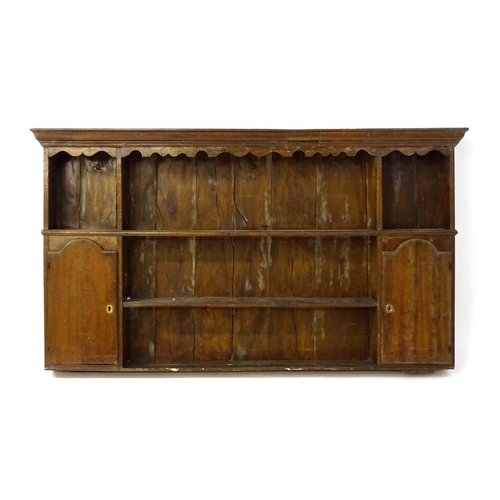 896 - An 18thC oak plate rack with a moulded cornice, shaped frieze and two cupboards. 74