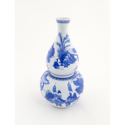 6 - A Chinese blue and white double gourd vase decorated with figures in a landscape. Approx. 16 1/4