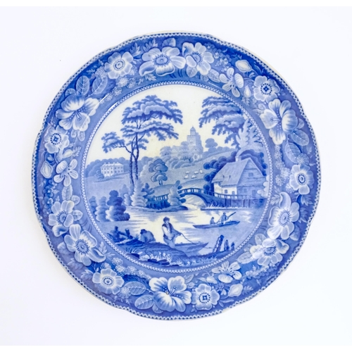 81 - A 19thC blue and white plate decorated with a rural river scene with cottage, bridge and figures in ... 