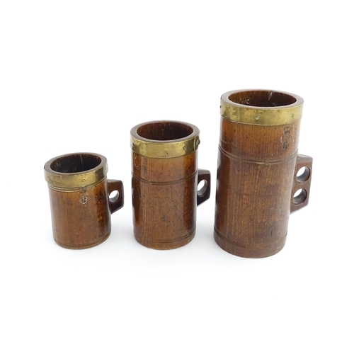 1125 - Treen : Three graduated Victorian and later oak dry measures with brass rims, comprising Quart, Pint... 