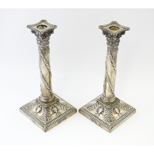 545 - A pair of Edwardian silver candlesticks of column form with urn, acanthus, and acorn and oak leaf ga... 