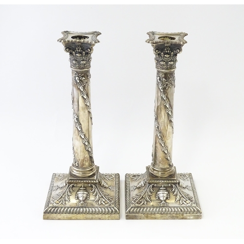 545 - A pair of Edwardian silver candlesticks of column form with urn, acanthus, and acorn and oak leaf ga... 