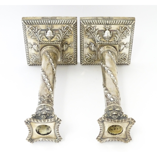 545 - A pair of Edwardian silver candlesticks of column form with urn, acanthus, and acorn and oak leaf ga... 