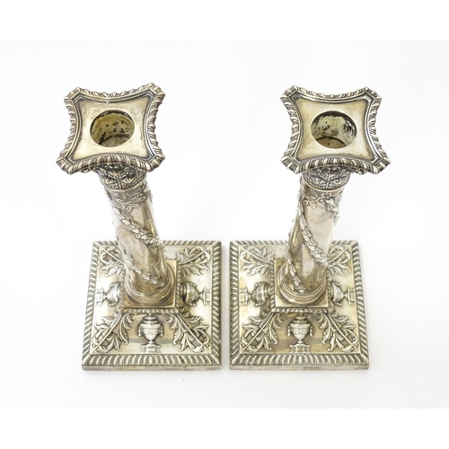 545 - A pair of Edwardian silver candlesticks of column form with urn, acanthus, and acorn and oak leaf ga... 