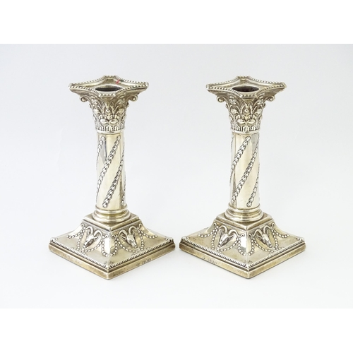 547 - A pair of Edwardian silver candlesticks of column form with swag and rams head detail, hallmarked Lo... 