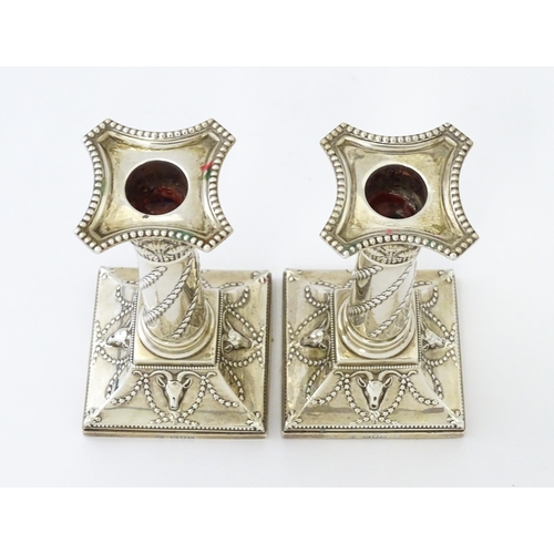 547 - A pair of Edwardian silver candlesticks of column form with swag and rams head detail, hallmarked Lo... 