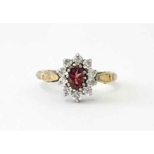 629 - A silver gilt ring set with central garnet bordered by white stones in a  cluster setting. Ring size... 