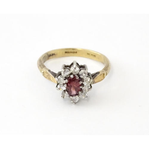 629 - A silver gilt ring set with central garnet bordered by white stones in a  cluster setting. Ring size... 