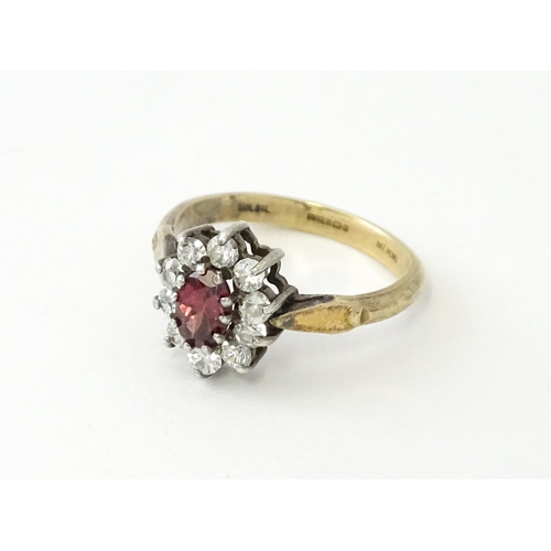 629 - A silver gilt ring set with central garnet bordered by white stones in a  cluster setting. Ring size... 