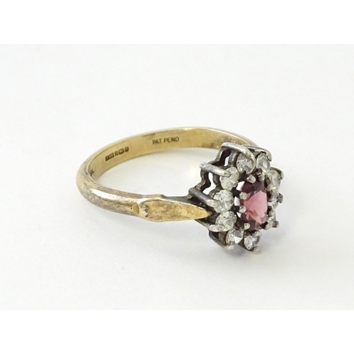 629 - A silver gilt ring set with central garnet bordered by white stones in a  cluster setting. Ring size... 