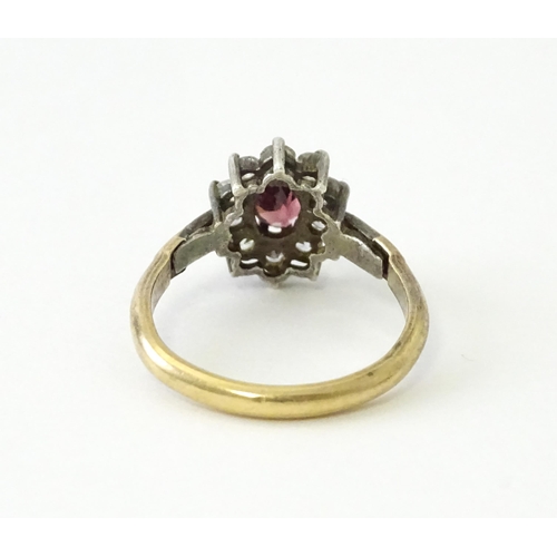 629 - A silver gilt ring set with central garnet bordered by white stones in a  cluster setting. Ring size... 