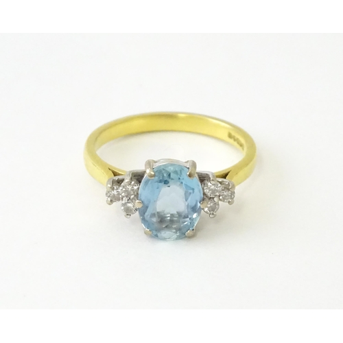 631 - An 18ct gold ring set with a central aquamarine flanked by diamonds. Ring size approx. M